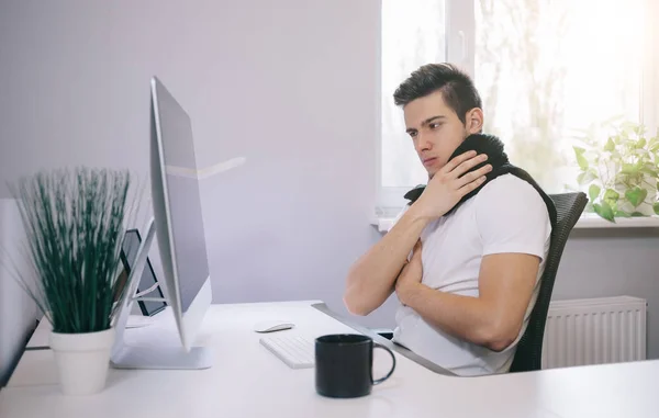 Un joven trabajador resfriado. Freelancer en bufanda y taza de té en la oficina. Diseñador de la garganta enferma en el lugar de trabajo . — Foto de Stock