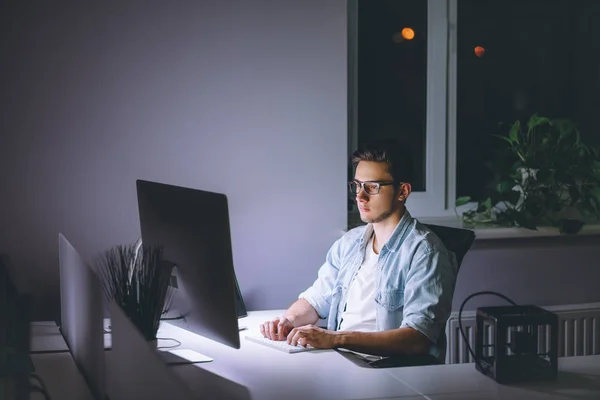 Jovem trabalhando no computador à noite no escritório escuro — Fotografia de Stock