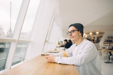 Adam tablo penceresi yakınındaki önünde oturuyor