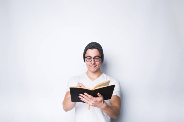 Düşünceli erkek öğrenci holding defter ve bakmak beyaz bir arka plan üzerinde izole