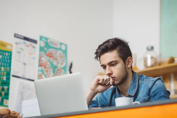 Junger ernster Mann mit Bart arbeitet am Laptop — Stockfoto