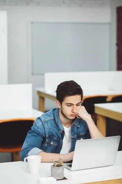 Ernster junger Kerl mit Bart arbeitet am Laptop — Stockfoto