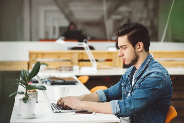 Un joven serio con barba trabajando en el portátil — Foto de Stock