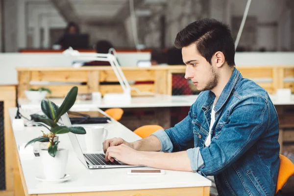 Un joven serio con barba trabajando en el portátil — Foto de Stock