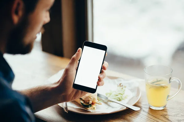 Genç adam telefon, restoranda oturan bakarak