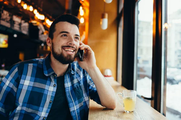 A fiatalember beszél a telefonon a café — Stock Fotó