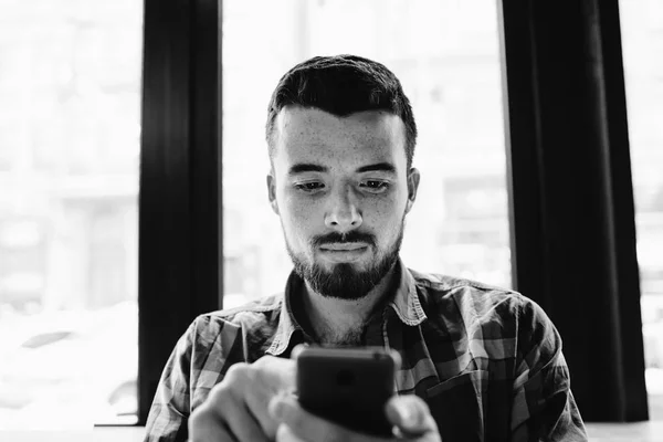 Fiatal férfi szakáll elfoglalva, és használ a smartphone — Stock Fotó