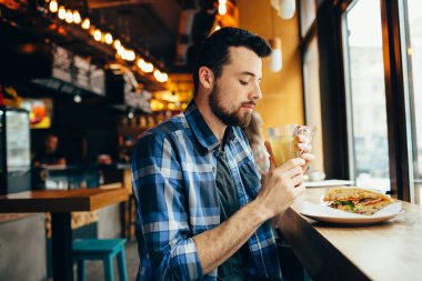 Genç adam restoranda oturan ve sıcak bir içki tadına bak.