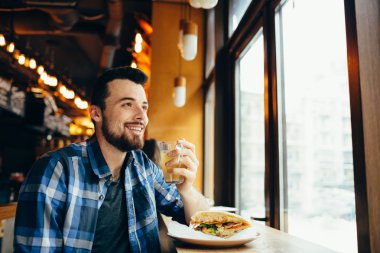Genç adam restoranda oturan ve sıcak bir içki tadına bak.
