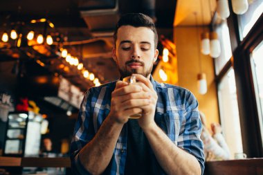 Genç adam restoranda oturan ve sıcak bir içki tadımı.