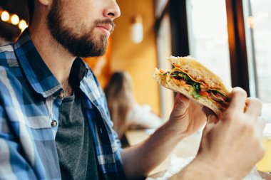Adam bir restoranda hamburger yemek