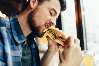 Adam bir restoranda hamburger yemek