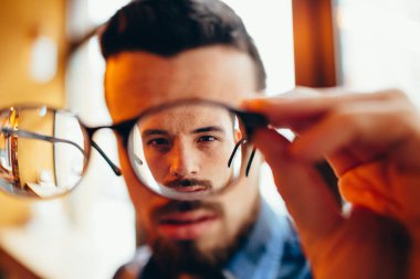 Closeup portrait of young man with glasses, who has eyesight problems clipart