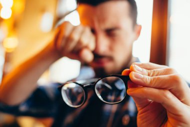 Closeup portrait of young man with glasses, who has eyesight problems clipart