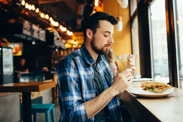Genç adam restoranda oturan ve sıcak bir içki tadına bak.