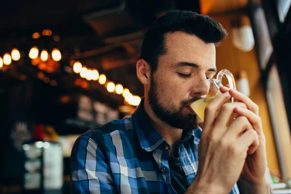 Genç adam restoranda oturan ve sıcak bir içki tadımı.