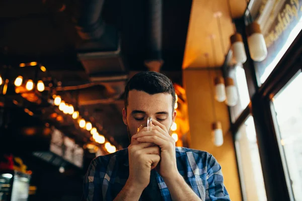 Jongeman is zittend in het restaurant en een warm drankje proeven. — Stockfoto