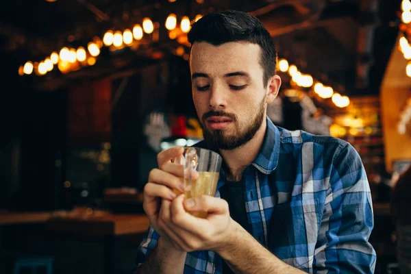 Genç adam restoranda oturan ve sıcak bir içki tadımı.