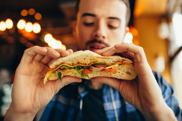 Adam bir restoranda hamburger yemek