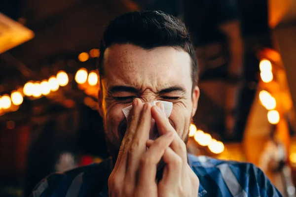 Atractivo joven sonándose la nariz — Foto de Stock