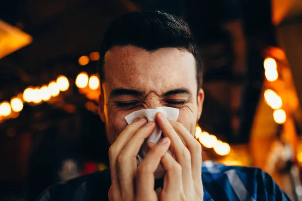 Atractivo joven sonándose la nariz — Foto de Stock