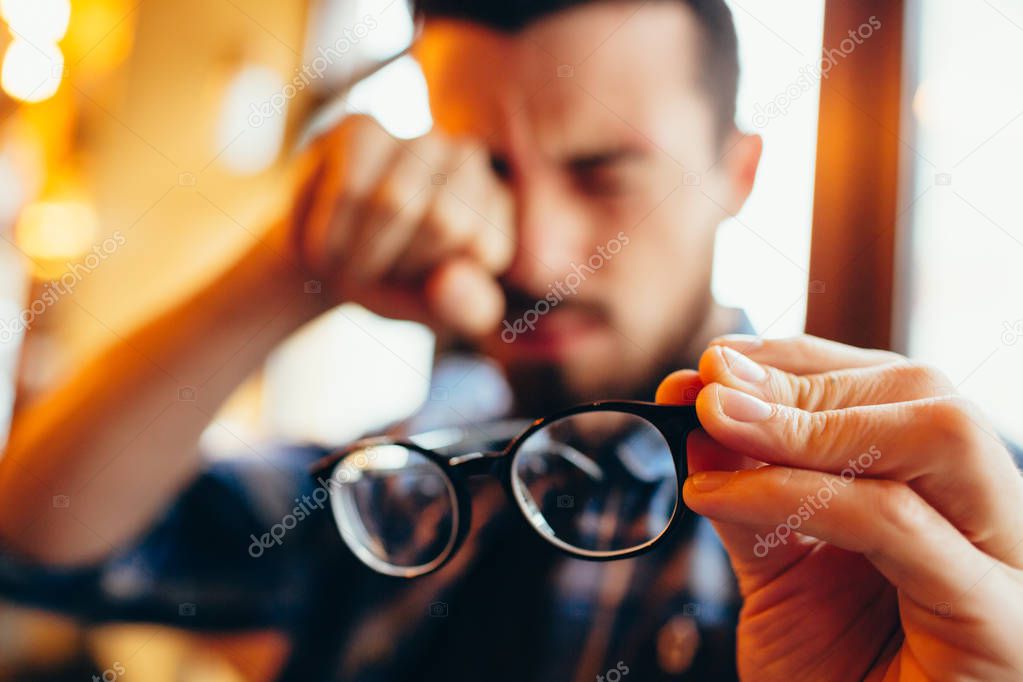 Closeup portrait of young man with glasses, who has eyesight problems