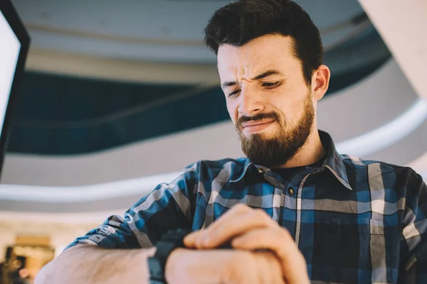 Ernstige man die op zijn horloge terwijl staande op de stedelijke achtergrond — Stockfoto