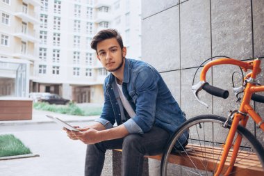 Genç adam bankta oturan tablet kullanma