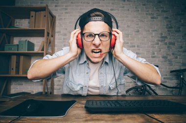 Genç adam evde oyun oynuyor ve video oynatıyor.