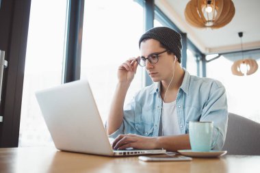 Giyim ve gözlük yakışıklı işadamı kafede bir laptop kullanıyor