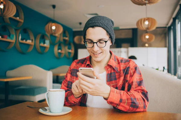 Aantrekkelijke jonge man of freelancer is zitten in Cafe en het drinken van thee. — Stockfoto