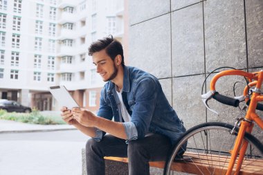 Genç adam bankta oturan tablet kullanma