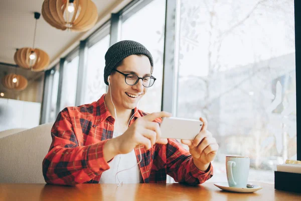 Aantrekkelijke jonge man of freelancer is zitten in Cafe en kijken naar video — Stockfoto