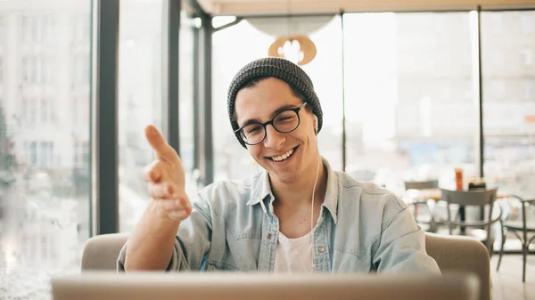 Bonito homem de negócios em desgaste casual e óculos está usando um laptop no café — Fotografia de Stock