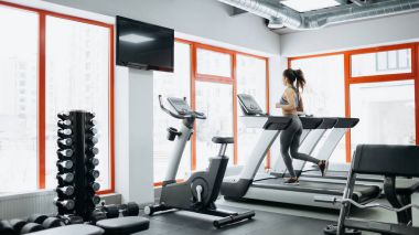 Genç güzel kadın koşu bandı üzerinde yapıyor yerleştirmek