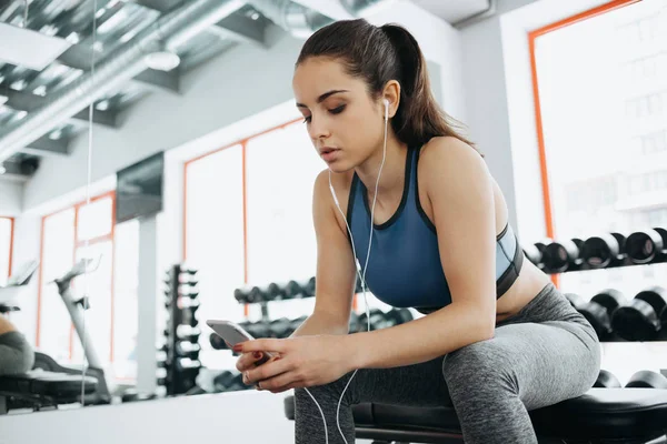 Jovem com fones de ouvido ouvindo música após treino duro no ginásio . — Fotografia de Stock