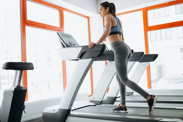 Jovem mulher bonita ajuste fazendo exercícios na esteira — Fotografia de Stock