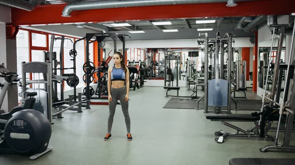 Mujer deportiva de pie con los brazos abajo en el gimnasio de fitness . — Foto de Stock