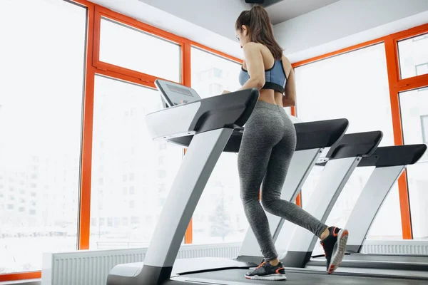 Jovem mulher bonita ajuste fazendo exercícios na esteira — Fotografia de Stock