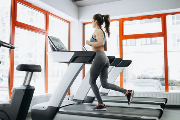 Jovem mulher bonita ajuste fazendo exercícios na esteira — Fotografia de Stock