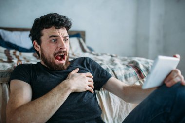 Rahatlatıcı ve bir tablet bilgisayarda bir Tv programı izlerken genç bir adam portresi