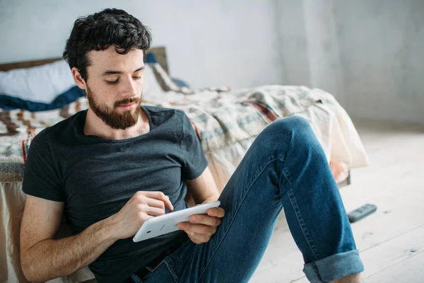 Portret van een tevreden jonge man ontspannen en kijken naar een Tv-show op een tablet-pc — Stockfoto