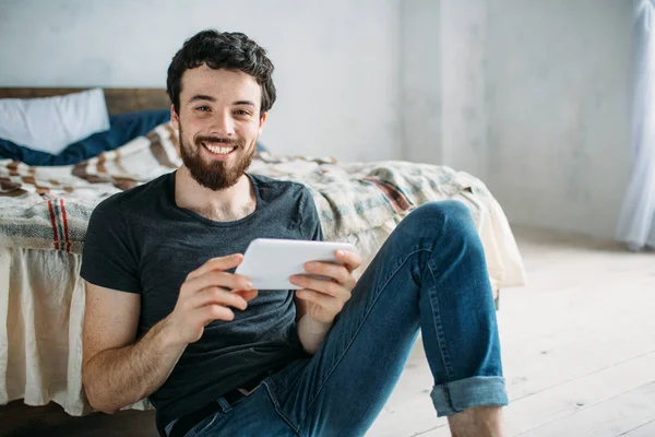 Retrato de um jovem feliz relaxando e assistindo a um programa de TV em um tablet — Fotografia de Stock