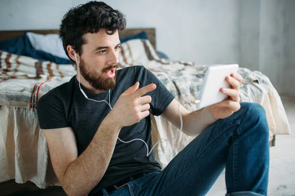 Porträt eines glücklichen jungen Mannes, der sich entspannt eine Fernsehsendung auf einem Tablet-Computer anschaut — Stockfoto