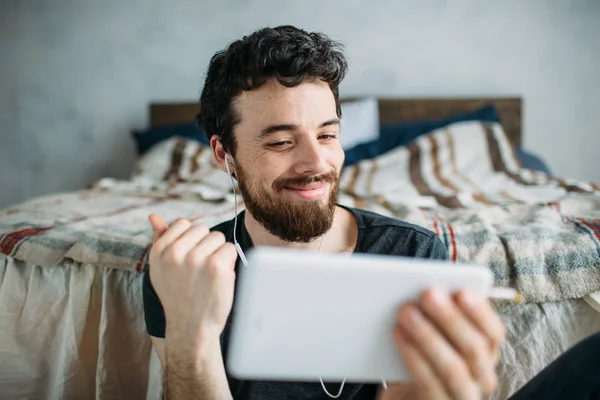 Retrato de um jovem feliz relaxando e assistindo a um programa de TV em um tablet — Fotografia de Stock
