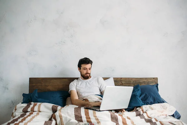 Schöner Mann sitzt im Bett — Stockfoto