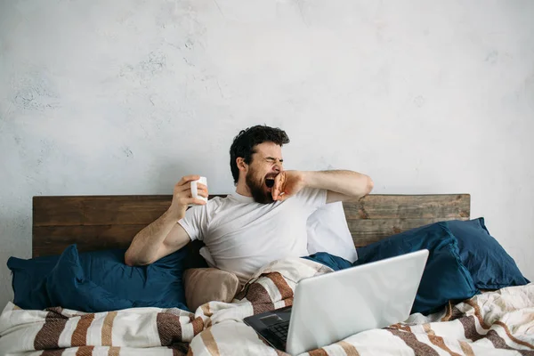 Knappe man in bed zitten en stretching — Stockfoto