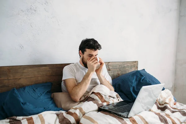 Bebaarde man liggen in ochtend bed met koffie of thee beker — Stockfoto