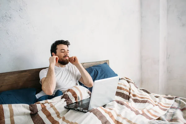 Bebaarde man liggen in ochtend bed met laptop — Stockfoto