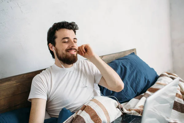 Bebaarde man liggen in ochtend bed met laptop — Stockfoto